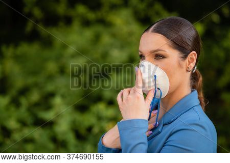 Beautiful Girl Puts A Medical Mask On Her Face On The Nature. Coronavirus And Covid-19 Protection