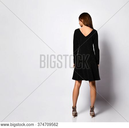 Rear View Of A Beautiful Young Female In A Glamour Black Minidress With A V-shaped Neckline On A Bac