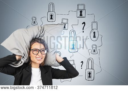 Portrait Of Stressed Young Businesswoman In Glasses Covering Her Ears With Pillow Near Gray Wall Wit