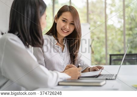 Two Asian Business Women Discussing In Office.