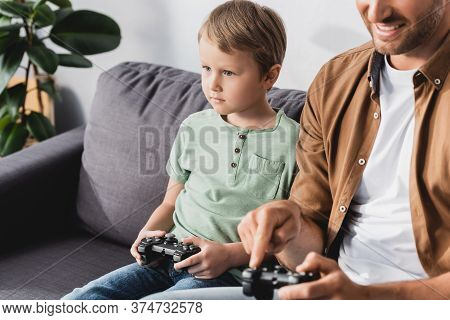Kyiv, Ukraine - June 9, 2020: Cropped View Of Smiling Man And Attenive Son Playing Video Game Wih Jo