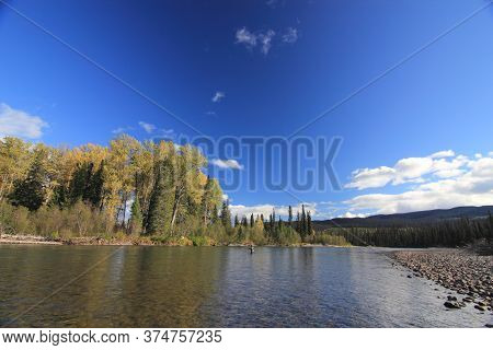 A Fisherman Fly Fishing In The Fall On An Autumn Day In British Columbia Canada While Standing In Cr