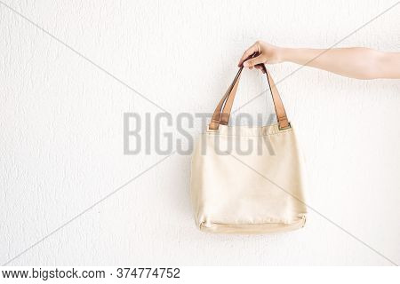 Hand Holding Rcraft Linen Eco Bag For Food Or Lunch On White  Wall Background. Eco-friendly Concept 