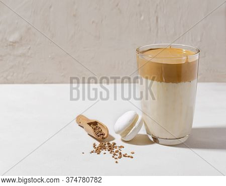 Korean Dalgon Coffee In A Tall Glass Glass Stands On A Light Background. Nearby Lies A White Macaroo