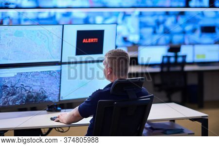 Male security operator working in a data system control room offices Technical Operator Working at  workstation with multiple displays, security guard working on multiple monitors  Male computer opera