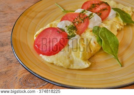 Breakfast On A Round Yellow Plate. Omelet And Ingredients Of Italian Caprese Salad. Cliced Fresh Moz