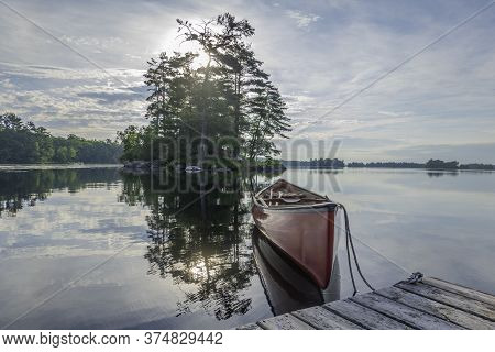 Canoe Tied To A Dock On The Calm Waters Of Stony Lake In The Morning,