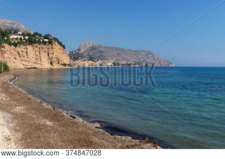 Tranquil Stone Beach With Turquoise Colored Ocean With View On Rocky Cliffs, Altea, Costa Blanca, Sp