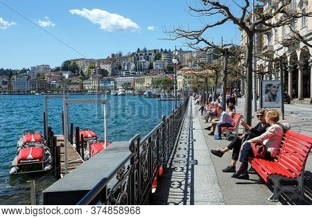 Lugano, Switzerland - April 17, 2018. People Relax On The Embankment Of The Lake Lugano In City Of L
