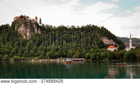View Of The Bled Castle And Church With Boats On The Lake In The Foreground