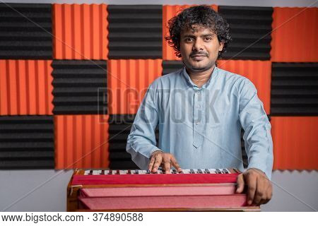 Young Musician Playing Indian Music Instrument Harmonium In Studio.