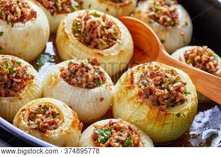 Close-up Of Caramelized Roasted Whole Onions Stuffed With Minced Lamb And Rice In A Black Ceramic Ba