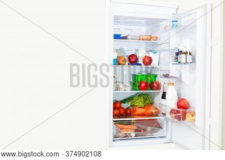 Top Freezer Kitchen Refrigerator With Doors Open And Shelves Full Of Groceries With Fresh And Frozen