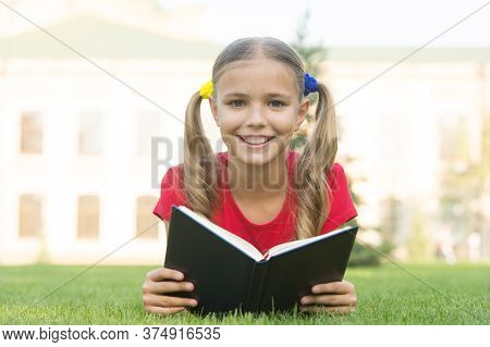 Open Your Imagination, Read. Happy Kid Read Book On Green Grass. Developing Imagination. Childhood I