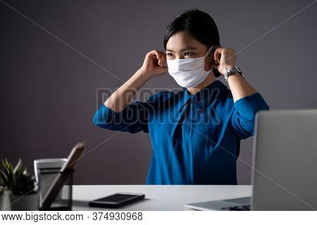 Asian Woman Wearing Protective Face Mask Working On A Laptop At Office. Wfh. Work From Home. Prevent