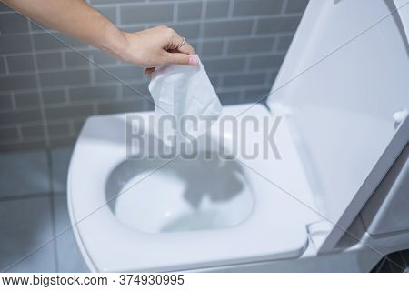 Woman Hand Throw Paper Towels In The Toilet Bowl. Cleaning, Lifestyle And Personal Hygiene Concept