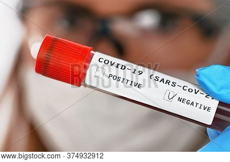 Hand In Blue Gloves Holding Vial With Blood, Label Says Covid 19 Test, Negative Result, Blurred Woma