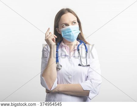 Female Doctor With Stethoscope Wearing Face Mask And Looking Careworn While Looking Aside And Thinki