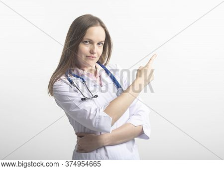 Happy Serious Female Young Doctor Wearing Uniform And Stethoscope Pointing With Finger On White Back