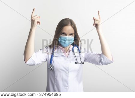 Serious Female Young Doctor Wearing Facial Mask Uniform And Stethoscope Pointing With Both Fingers O
