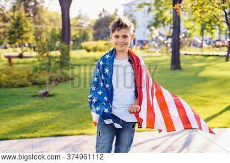 A Young Boy In A Red Plaid Shirt And White T-shirt Happily Standing In The Park With The Stretched U