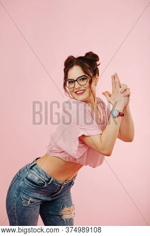 Cute Eccentric Overly Happy Girl Making Holding Gun Gesture Over Pink
