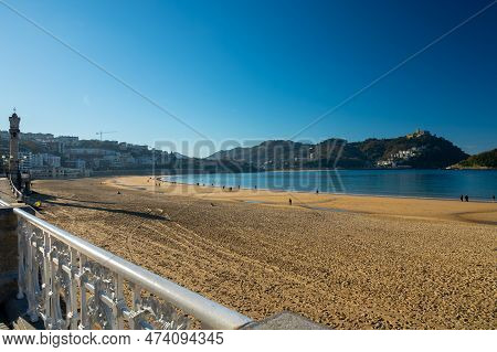 Walking On Promenade Along White Sandy La Concha Beach In Central Part Of Donostia Or San Sebastian