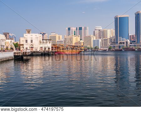 View Along The Creek Towards Deira With Large Dhow Tour Boats Docked By The Al Seef Boardwalk In Dub