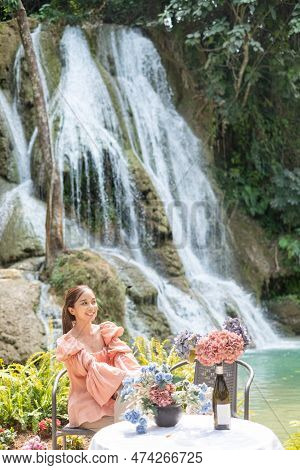 Young Asian Woman Sitting On A Chair In Front Of The Khoun Moung Keo Waterfall