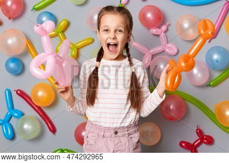 Extremely Excited Festive Little Girl  With Pigtails Standing Against Gray Decorated Colorful Wall H