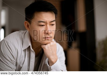 Despaired Lonely Middle Aged Asian Man Thinking And Looking Down, Sitting In Living Room, Free Space