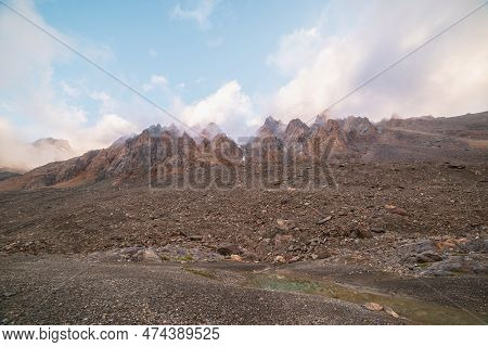 Scenic Alpine Landscape With Rocky Mountains In Dense Low Clouds In Morning Sunlight. Colorful Mount