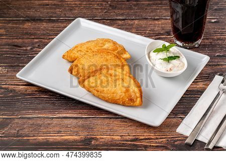 Beef Cheburek On A Wooden Table. Deep Fried Beef Dumplings With Meat And Onions. Turkish Name Ci Bor