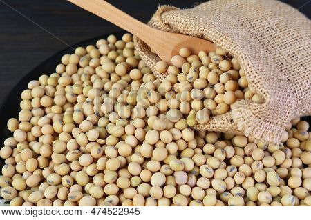 Dried Soybeans Scattered From Burlap Bag On To Black Wooden Table
