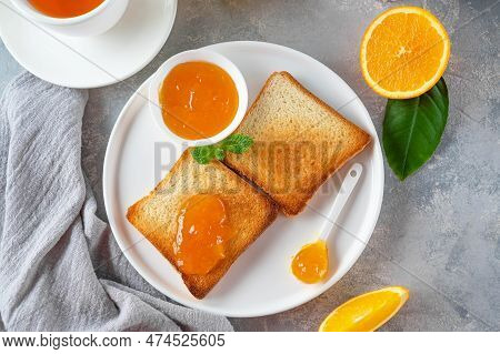 Toasts With Orange Marmalade Or Orange Jam With Cup Of Tea On A Gray Background. Delicious Breakfast