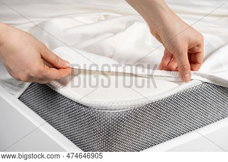A White Satin Sheet With An Elastic Band Is Put On The Mattress Of The Bed, A Close-up Of The Hands.