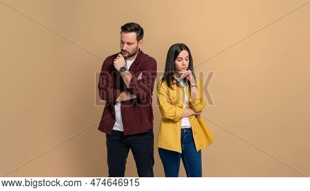 Disappointed Young Boyfriend And Girlfriend Dressed In Casuals With Hands On Chins Looking Down. Unh
