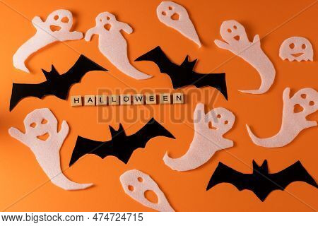 White Ghosts And Bat Craft For Halloween Party. Wrapping Paper Ghost On Orange Background Top View. 