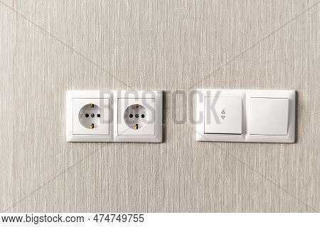 New White Switch And Socket On The Light Wall.  Electric Light Switch And Socket On The Empty Wall. 