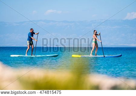 Couple Riding Sup Stand Up Paddle On Vacation.