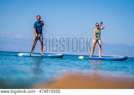 Couple Riding Sup Stand Up Paddle On Vacation.
