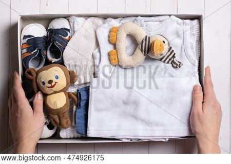 Female Hands Put Children's Clothes, Shoes And Toys Into A Box. Second Hand, Clothing Recycling Conc