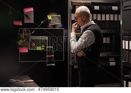 Senior Officer Working Overtime At Mysterious Criminal Case, Analyzing Files With Scene Crime Eviden