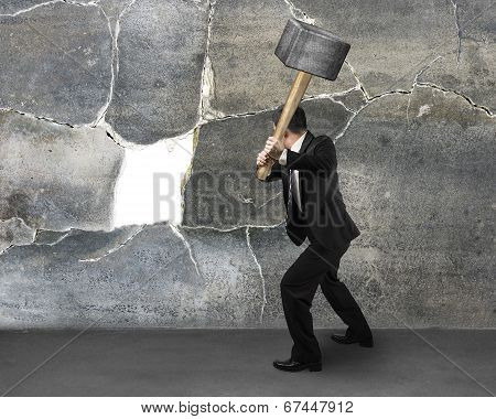 Businessman Holding Sedgehammer To Crack Wall