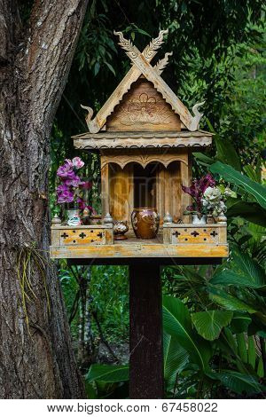 Spirit House In Thailand With Flowers In Vases And Some Wreathes