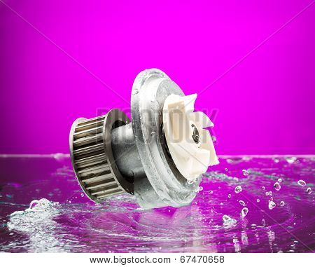 Auto Parts, Engine Cooling Pump In Spurts Of Water On Purple Background.