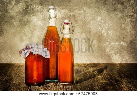 Bottles Filled With Yellow Syrup And Jam On Kitchen Table