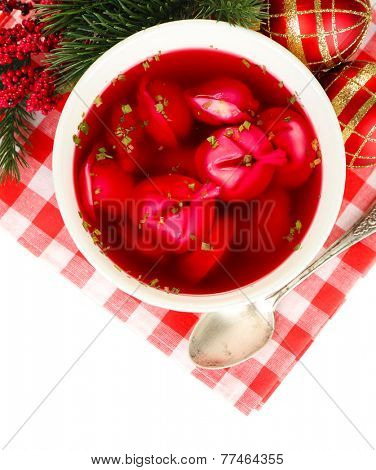Traditional polish clear red borscht with dumplings and Christmas decorations isolated on white