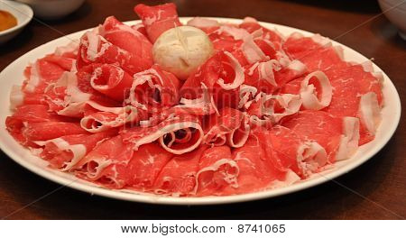 En tallerken med frisk tyndt oksekød skiver for orientalsk hotpot