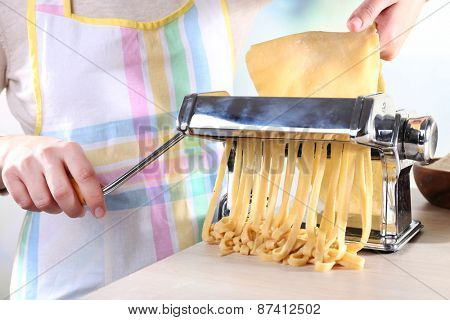Woman making noodles with pasta machine, closeup